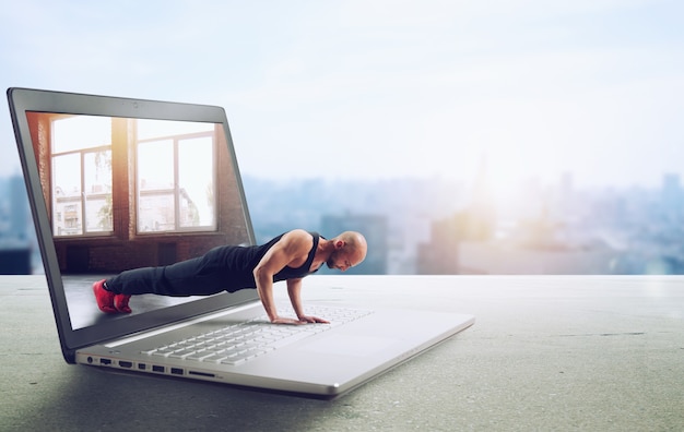 Personal trainer does gym lesson through internet and laptop