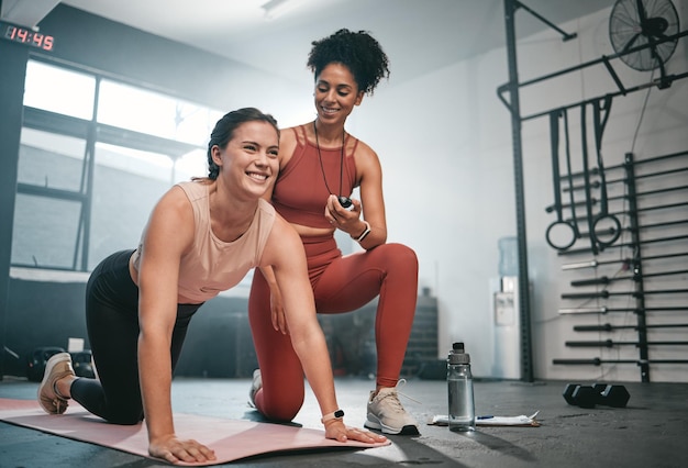 Esercizio di personal trainer e cronometro con una donna di colore che istruisce un cliente in palestra durante il suo allenamento fitness o allenamento per la salute e un'atleta pronta a planare con un tempo di registrazione dell'allenatore