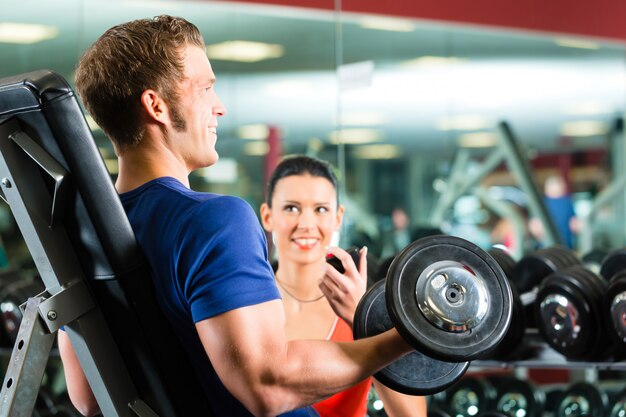 Personal trainer in palestra e allenamento con manubri