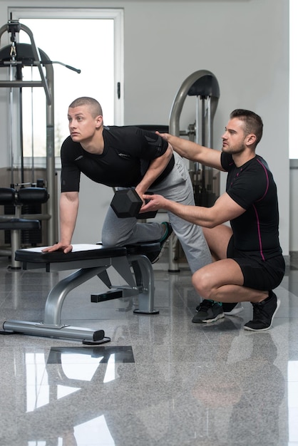 Personal Trainer Helping Client In Gym