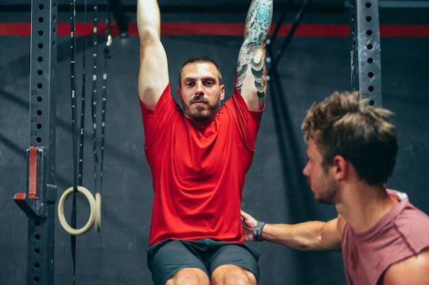 Personal trainer helping a strong man to do pull ups