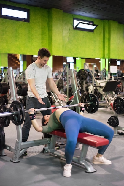 Personal trainer helping woman at gym.