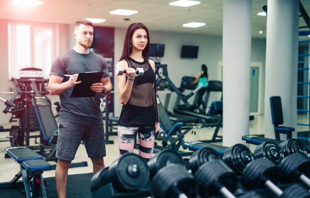 Personal trainer helping woman working with heavy dumbbells Personal fitness instructor Personal training