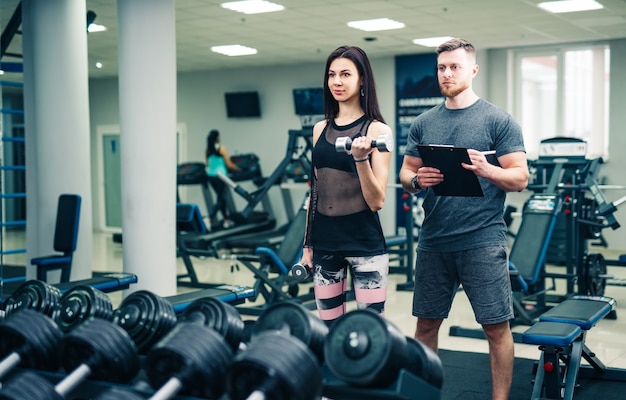 Personal trainer helping woman working with heavy dumbbells. Personal fitness instructor. Personal training.