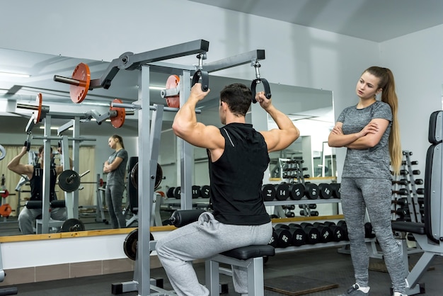 Personal trainer helping work with barbell in gym