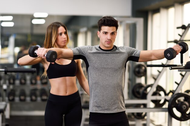 Personal trainer helping a young man lift weights