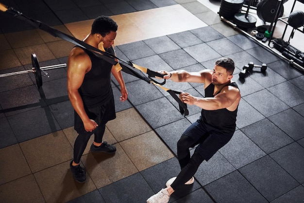 Personal trainer is on job African american man with white guy have workout day in gym