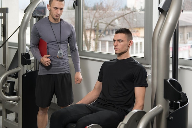 Personal Trainer maakt aantekeningen terwijl de man zijn benen traint