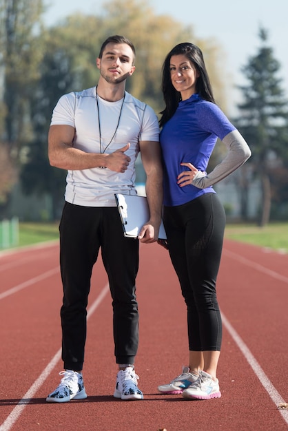 Personal Trainer maakt aantekeningen terwijl jonge vrouw oefenen in stadspark gebied Training en oefenen voor uithoudingsvermogen Gezonde levensstijl Concept buiten