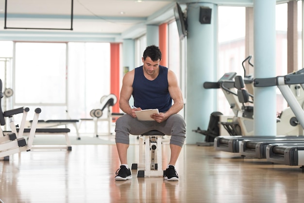 Personal Trainer Takes Notes On Clipboard In a Gym