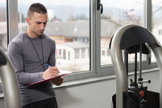 Il personal trainer prende appunti mentre l'uomo esercita le gambe