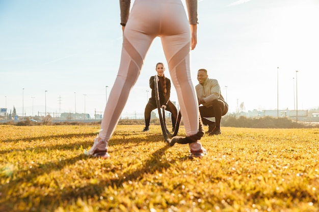 Photo personal trainer training two girls with ropes