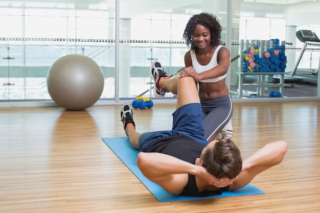 Personal trainer working with client on exercise mat