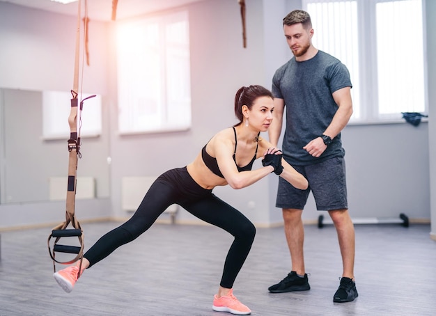 Personal trainer working with his client in gym young and\
beautiful woman working out with dumbbells in gym healthy life and\
sport fit fitness concept