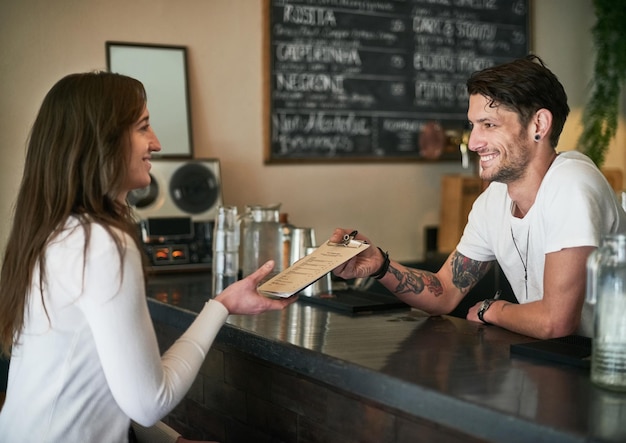 Personally Id recommend this one Shot of a friendly young bartender helping a customer with her order across the bar counter