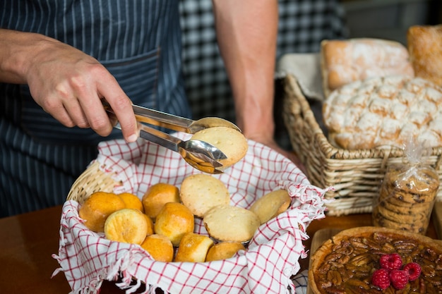 Personeel dat koekjes met tong in bakkerijwinkel houdt