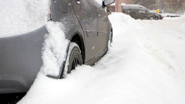 Personenauto vast in sneeuw, zijaanzicht. auto geblokkeerd in de tuin door sneeuwjacht na zware sneeuwstorm. slechte weersomstandigheden.