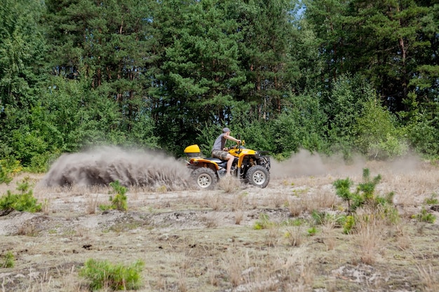 Personenvervoer een gele quad atv al terreinvoertuig op een zandig bos. extreme sportbeweging, avontuur, toeristische attractie.