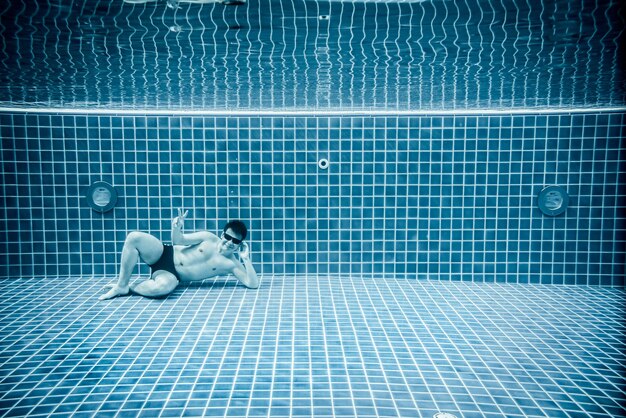 Persons lies under water in a swimming pool