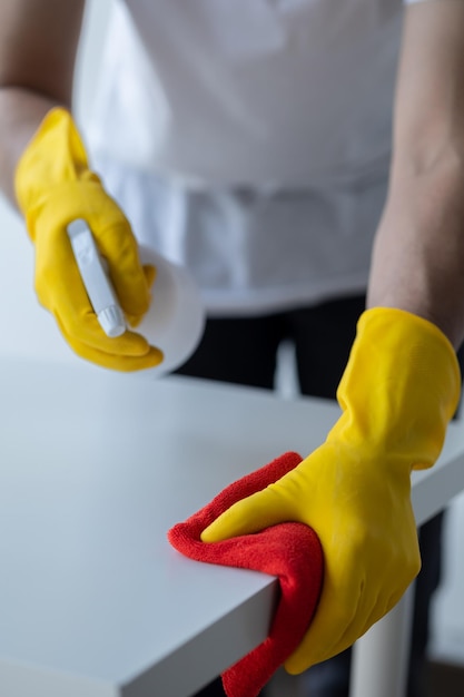 Persoon die de kamer schoonmaakt schoonmaakpersoneel gebruikt een doek en spuit ontsmettingsmiddel om de tafel in de kantoorruimte van het bedrijf af te vegen Schoonmaakpersoneel Schoonhouden in de organisatie