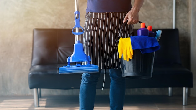 Persoon die de kamer schoonmaakt Schoonmaakpersoneel staat met een emmer schoonmaakapparatuur Schoonmaakpersoneel Zorgt voor netheid in de organisatie