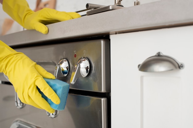 Foto persoon die de keuken met handschoenen schoonmaakt