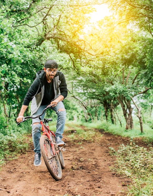 Persoon die een fiets berijdt op het platteland Portret van een man in pet die een fiets berijdt op een landweg Fietser persoon op zijn fiets op een landwegbos Een man die een fiets berijdt op het platteland