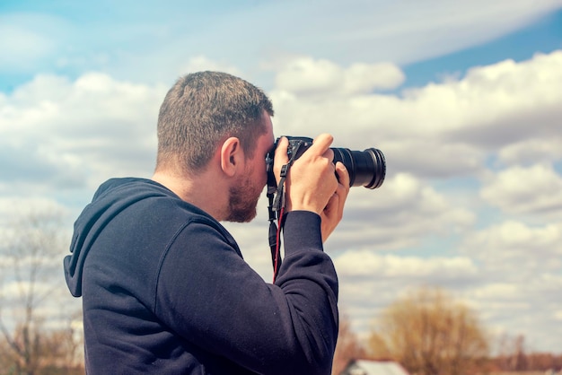Persoon die een foto maakt met een reflexcamera Man met zwarte fotocamera in warme zomerdag