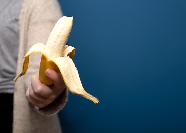 Persoon die een geel banaanfruit in hand houdt, die gezond concept weggeeft