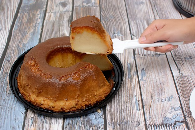 Persoon die een zelfgemaakte broodpudding snijdt op houten tafel