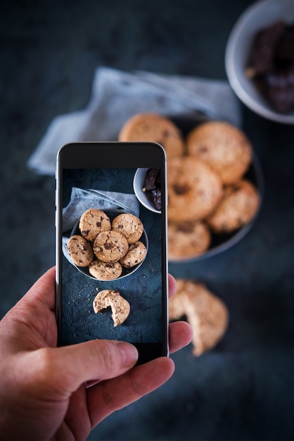 Persoon die foto met een telefoon neemt aan sommige koekjes met chocolade