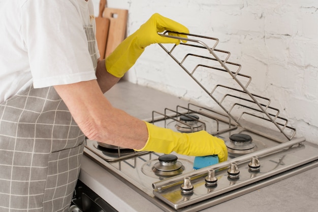 Foto persoon die het fornuis met handschoenen wast