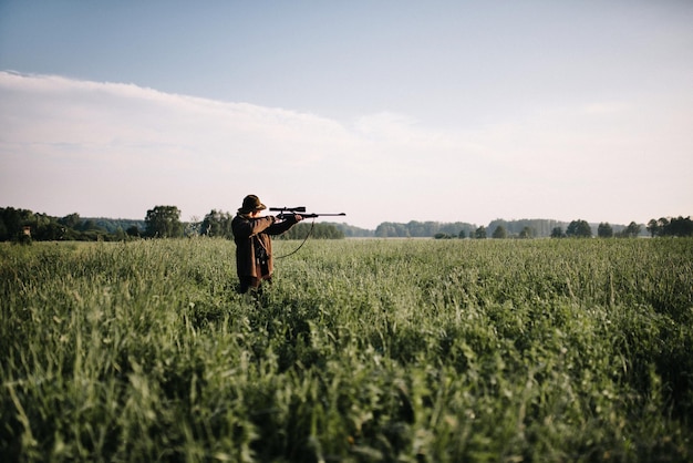 Foto persoon die met een pistool in het gras op het veld richt