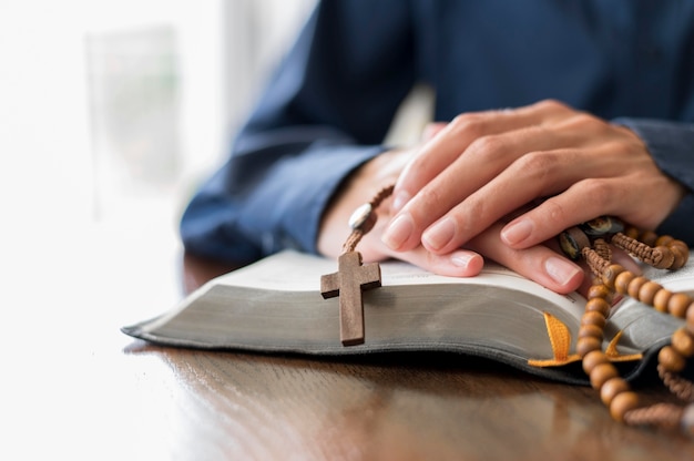 Persoon die met open heilig boek en rozenkrans bidt