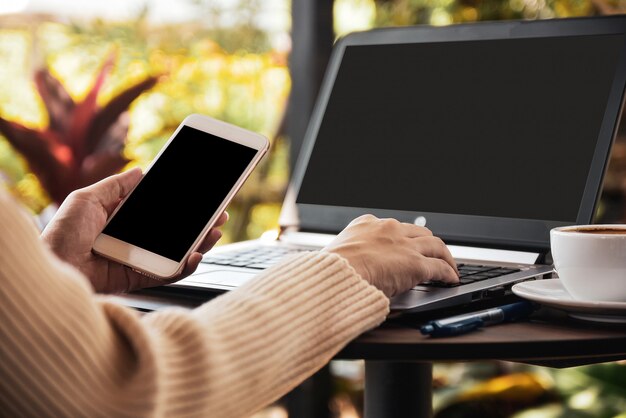 Persoon die mobiel slim houdt tijdens het gebruik van de laptop