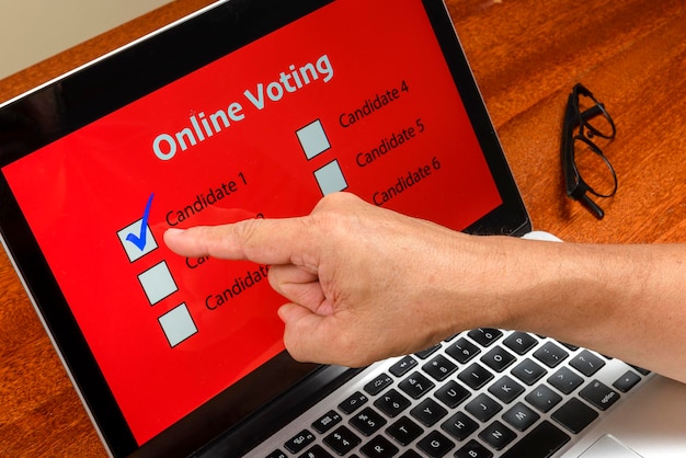 Foto persoon die op de computer via het internet stemt met de tekst online stemmen