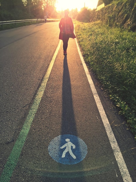 Foto persoon die op een verlichte straat loopt