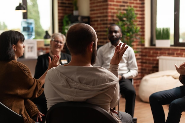 Persoon die prestatie deelt met een groep mensen tijdens een vergadering, zittend in een cirkel. Man tijdens therapiesessie praten over alcoholverslaving met revalidatiepatiënten en psychotherapeut.