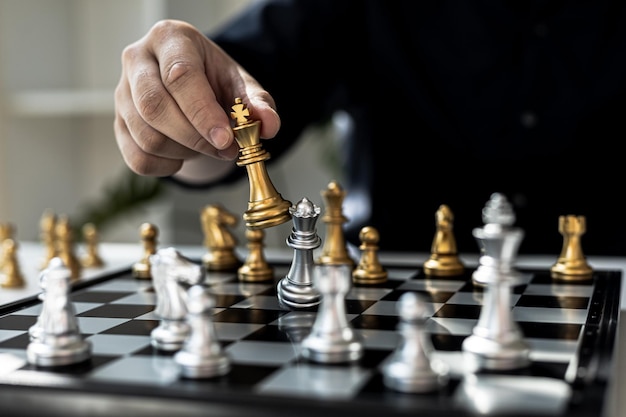 Persoon die schaakbordspel speelt, het conceptbeeld van een zakenman met schaakstukken zoals zakelijke concurrentie en risicobeheer, het plannen van bedrijfsstrategieën om zakelijke concurrenten te verslaan.