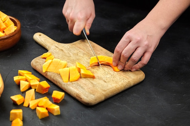 Persoon een pompoen snijden op houten snijplank op stenen tafel