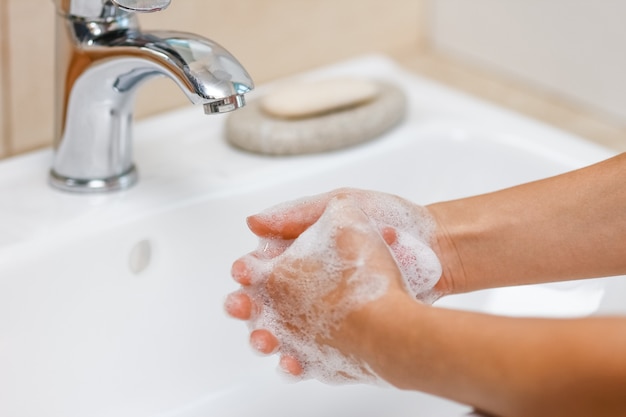 Persoon Handen wassen met zeep onder de kraan met water