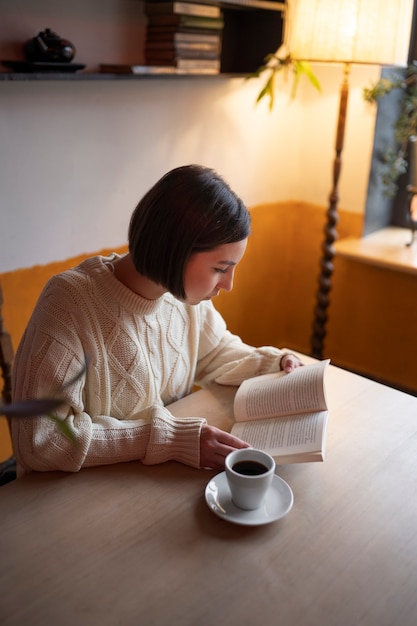 Persoon in een café die een boek leest terwijl hij koffie drinkt