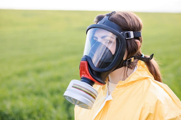 Persoon in overall en gasmasker oproep om de planeet te redden terwijl hij op het groene veld staat bij zonsondergang Concept van slechte ecologie en milieubescherming