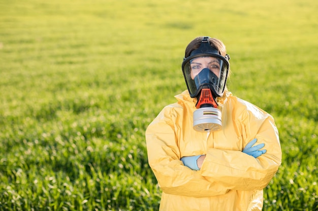 Persoon in overall en gasmasker roept op om de planeet te redden terwijl hij op een groen veld staat bij zonsondergang