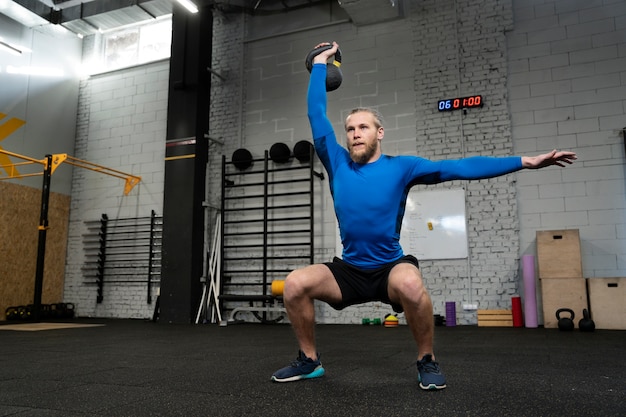 Persoon in sportgymnastiek die kettlebells gebruikt