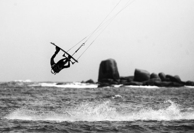 Persoon kitesurfen over zee tegen de lucht