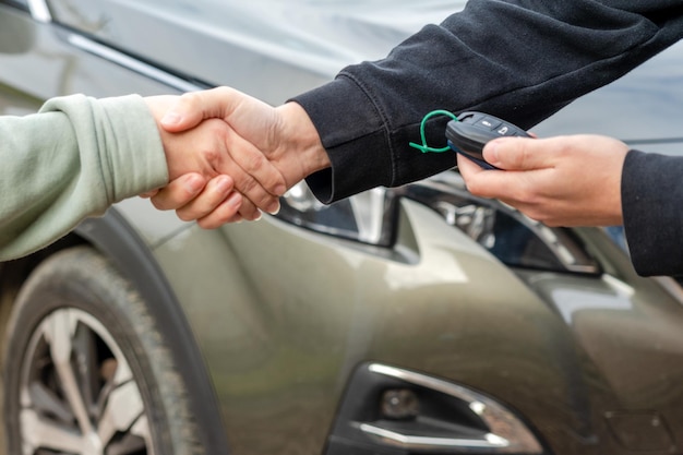 Persoon met een autosleutel in de hand staat voor auto Deal van het kopen of huren van een auto