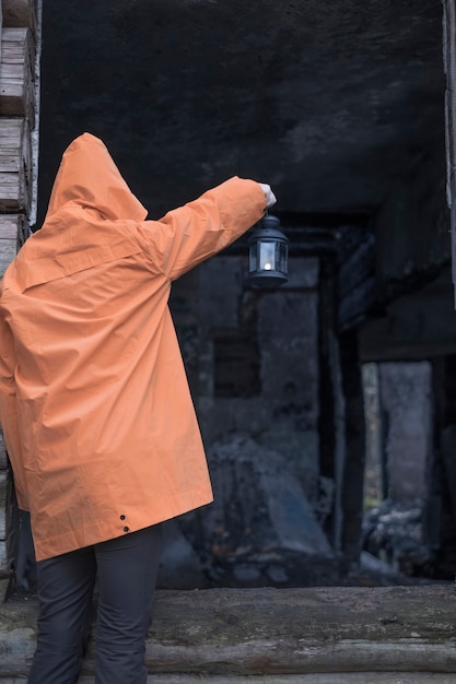 Persoon met een lantaarn kijkt in een oud verwoest afgebrand huis