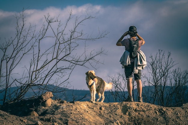 Persoon met een rugzak wandelen met een hond onder het zonlicht op een regenachtige dag