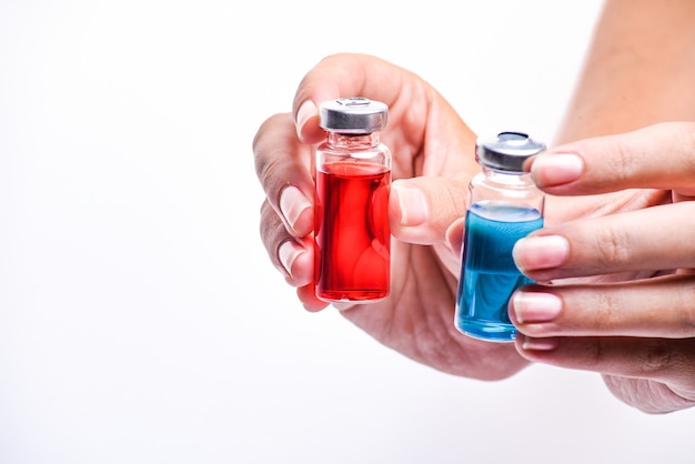 Foto persoon met parfumflesjes met rode en blauwe vloeistoffen